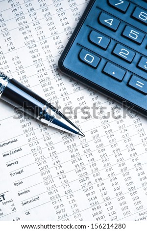 top of view of a business pen near a calculator on financial newspaper under light tint blue