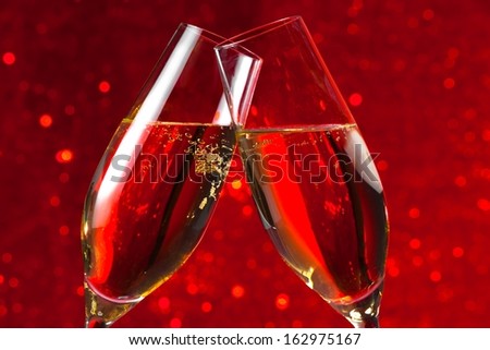 detail of two champagne flutes make cheers on red light bokeh background