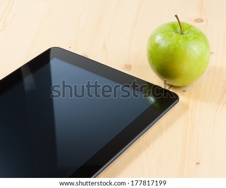 smart digital tablet pc and green apple on wood table, concept of learn new technology