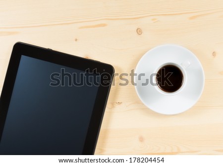 top of view cup of coffee and tablet on wood table, concept of new technology