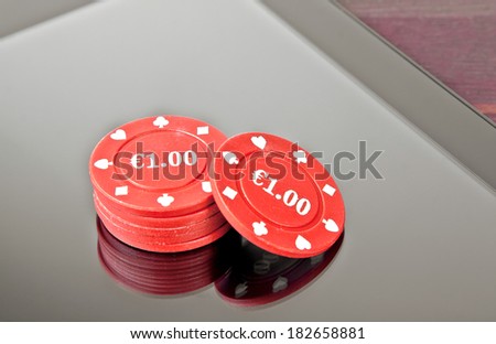 gambling chips on digital tablet pc on old wood table, concept of texas game on-line