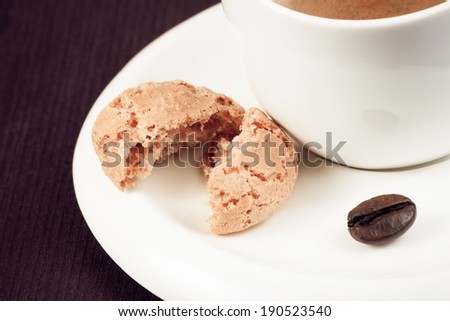close-up of cup of italian espresso coffee and biscuit near coffee bean on old wood