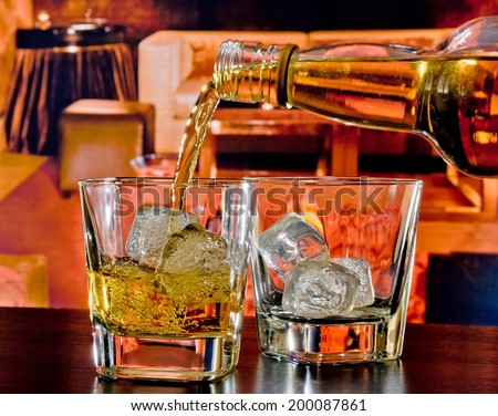 barman pouring whiskey in a lounge bar on wood table