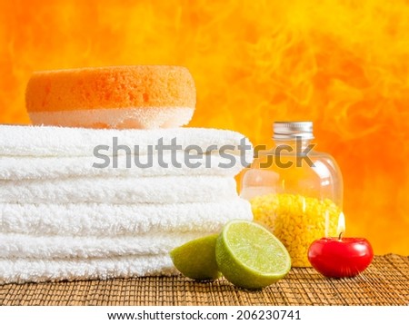 Spa massage border background with towel stacked,red candle and lime on orange background