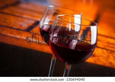two red wine glasses on wood table with warm atmosphere background, festive and fun concept