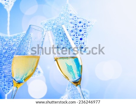 champagne flutes with golden bubbles make cheers on blue christmas lights decoration background, christmas atmosphere