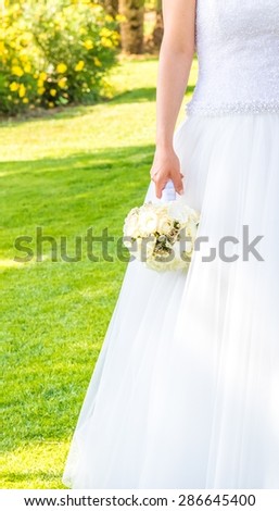 bride holds in hand a wedding bouquet of flowers in a green garden