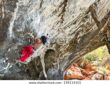 KRABI, THAILAND - MARCH 14, 2014: Rock climbers climbing on Railay beach in Krabi, Thailand. Railay beach is one of the most popular rock climbing locations in Asia.