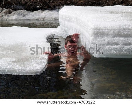 young man extremal swimming among ice floats