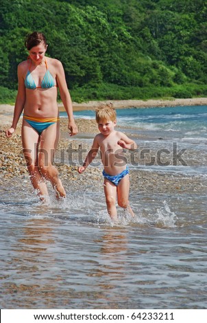 happy family of mother with kid running on the sea beach