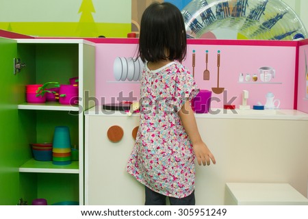 Asian Chinese little girl role-playing at kitchen.
