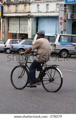 A man bicycling in an old town in Malaysia, Asia.