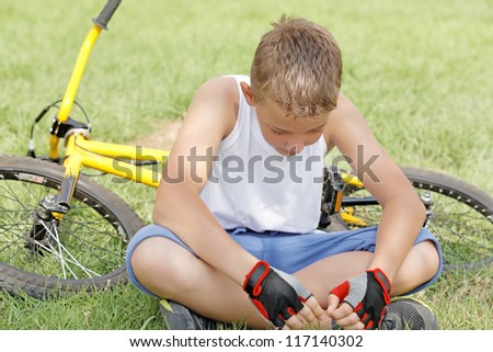 the guy sitting next to the bike outside in the summer