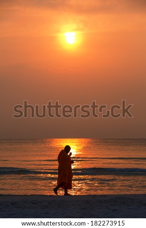 Silhouette of monk walk on the beach , Huahin , Thailand