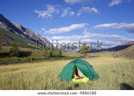 tent near the river and remote mountain peaks