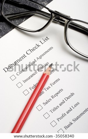 Red pencil and glasses on a document check list