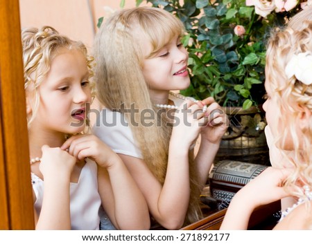 Two girls looking at themselves in mirror and trying on beads