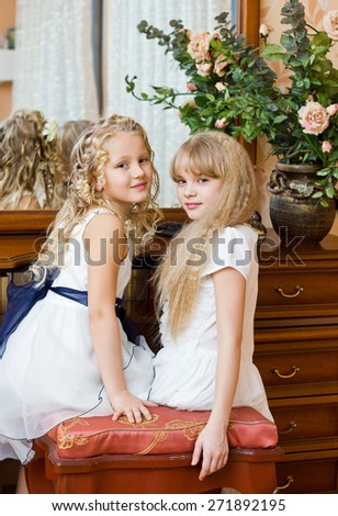 Two little girl sitting at mirror in bed room preparing for party