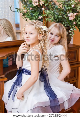 Two little girl sitting at mirror and preparing for party
