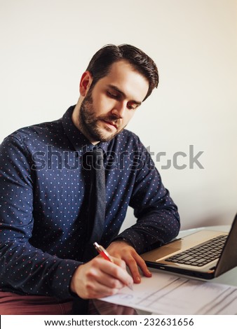 Business man filling out paper on desk in an office