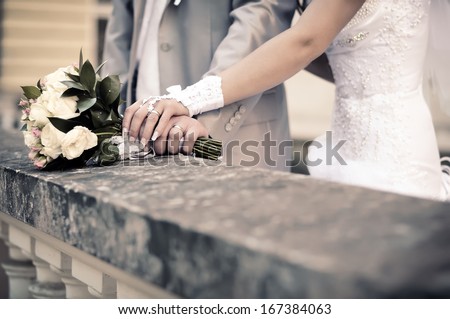couple\'s hands holding wedding bouquet of flowers. Imitation of antiquity.