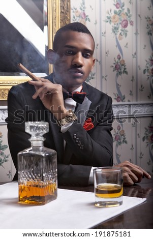 Elegant, handsome black man enjoy whiskey and cigar in the club