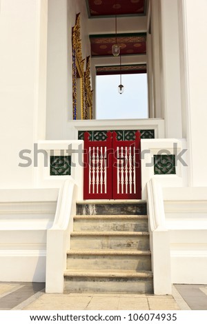 The stairs of a white church blocks with a red wooden door.
