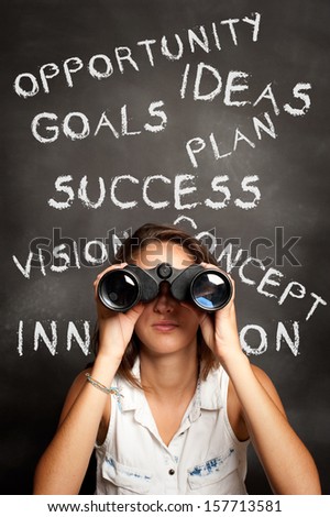 young woman using binoculars in front of chalkboard with motivation words