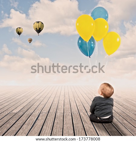 baby boy holding bunch of balloons on a wharf