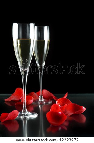 champagne glasses with petals of rose isolated on black background