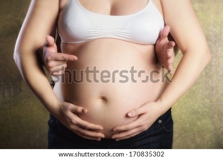 Pregnant woman be embraced her husband with a pointing finger on a child\'s name