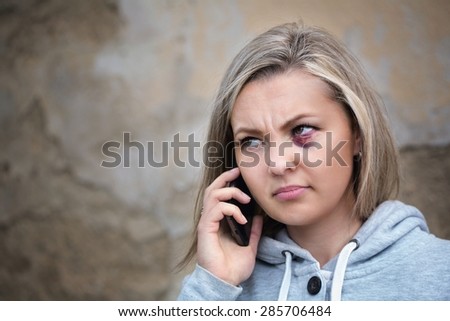 Scared woman with bruise on face calling to get help