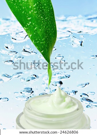 Cosmetic cream with fresh green leaf on background drops water