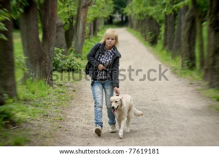 Blond woman walking with her golden retriever dog in the park