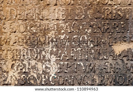 Ancient and dilapidated inscription in Latin carved in stone on the wall of the church in Germany