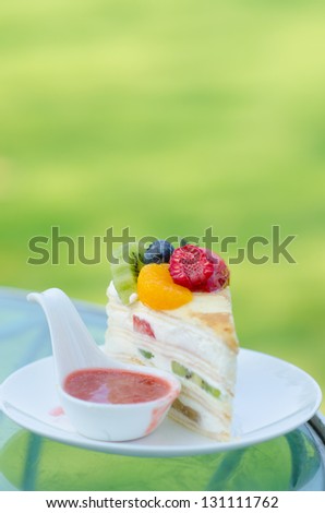sweet cake with fruits on plate and green background