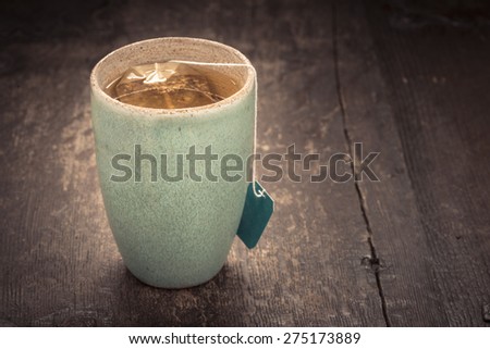 Closeup of cup filled with fresh hot tea and a teabag. Food and drink backdrop showing a mug of hot beverage served. It can be used as a conceptual image for breakfast time.