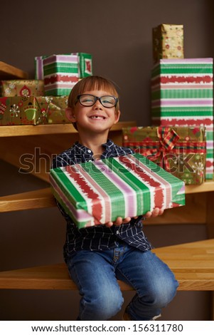 Smiling boy ready to open Christmas presents on the stairs of his house