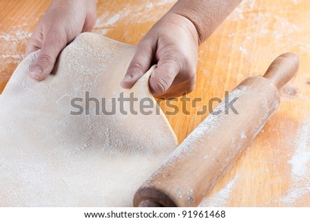 stretched dough with a rolling pin and flour