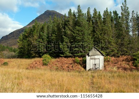 An old derelict down shed with a old worn out bicycle resting against it in a remote area of the scottish highlands.