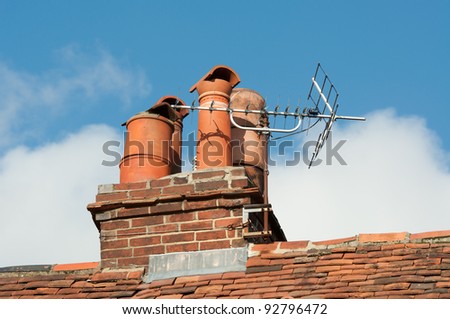 Old clay chimney pots and brick chimney stack on old tiled roof complete with TV aerial .