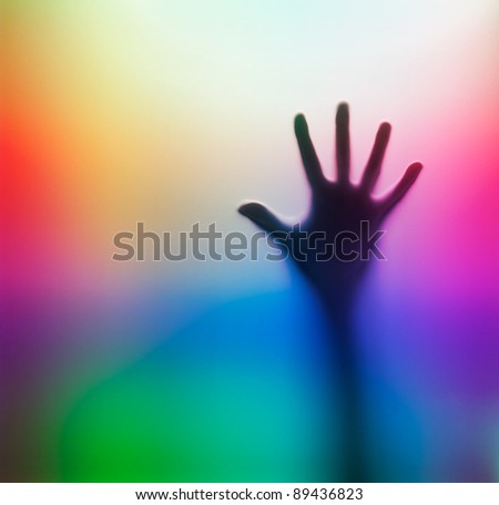 Human hand behind glass. Colorful abstract background.
