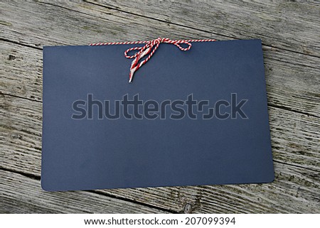 Blue folder on a wooden background with a red and white string tied bow.
