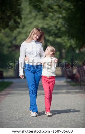 Mother and daughter walking in the summer park