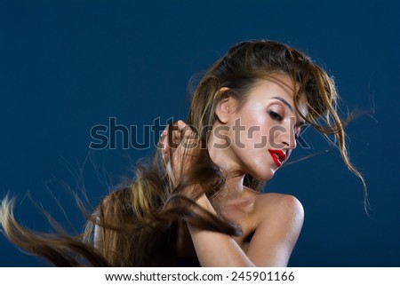 Studio portrait of a woman. Wind generator is directed to long hair.