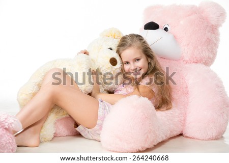 Cute little girl school age plays with a teddy bear. Isolated on white background.