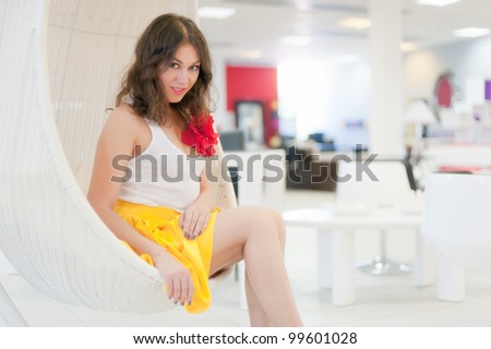 Picture an elegant young woman sitting in white hung seat somewhere in the fashionable interior