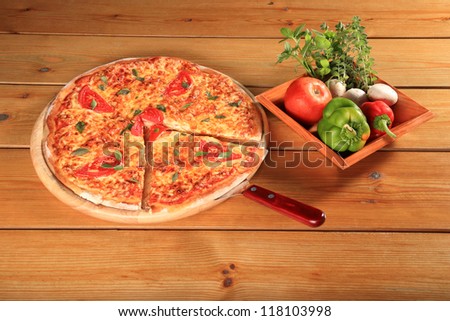 fresh pizza margarita on a wooden plate and bowl with vegetables
