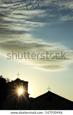 silhouette of a small church with the sun beams coming through