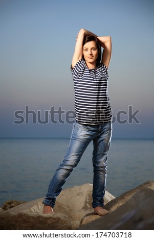 portrait of a young beautiful girl on a rocky beach with blue sky late in the afternoon